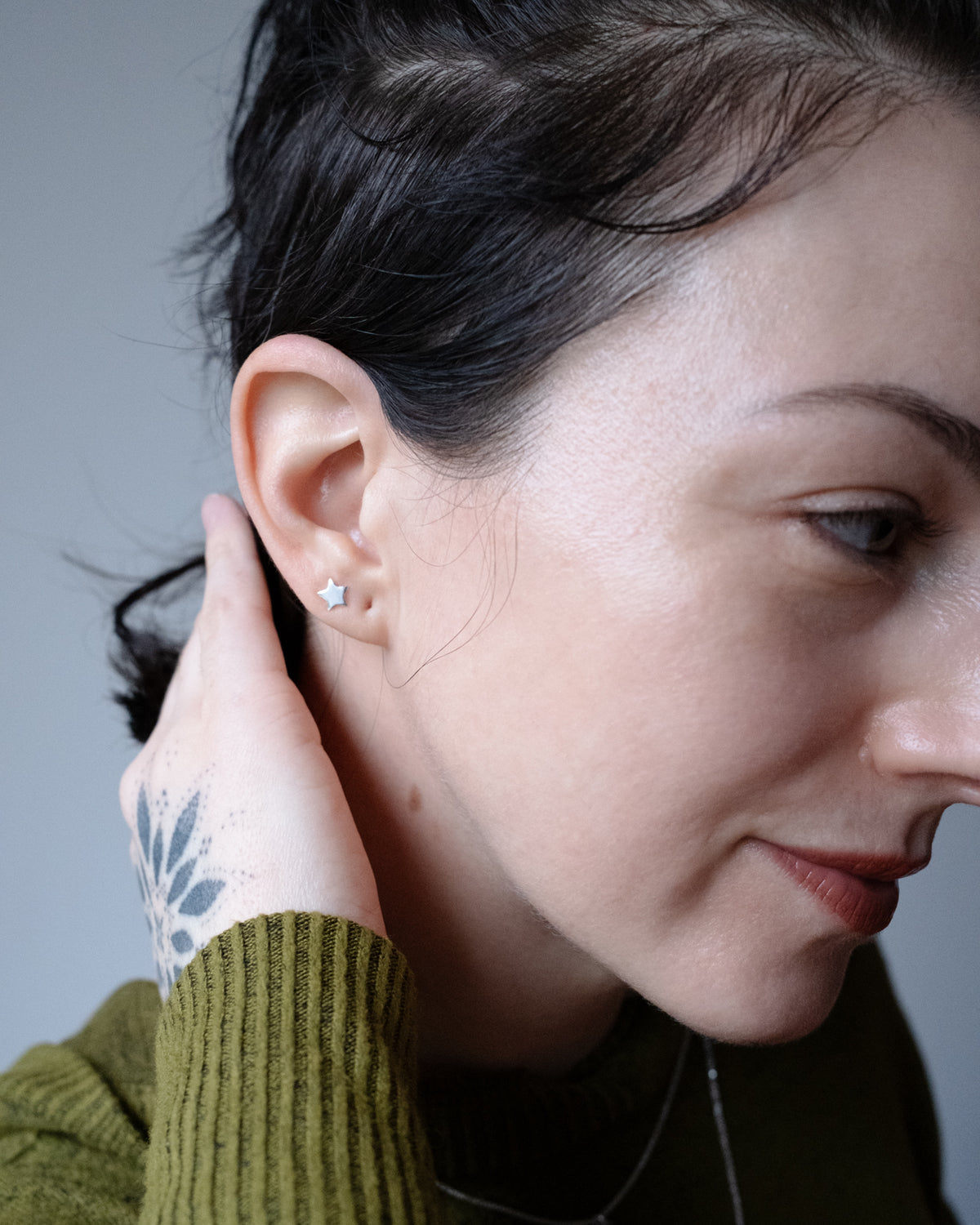 Model wearing sterling silver moon and star stud earrings, hand at her neck