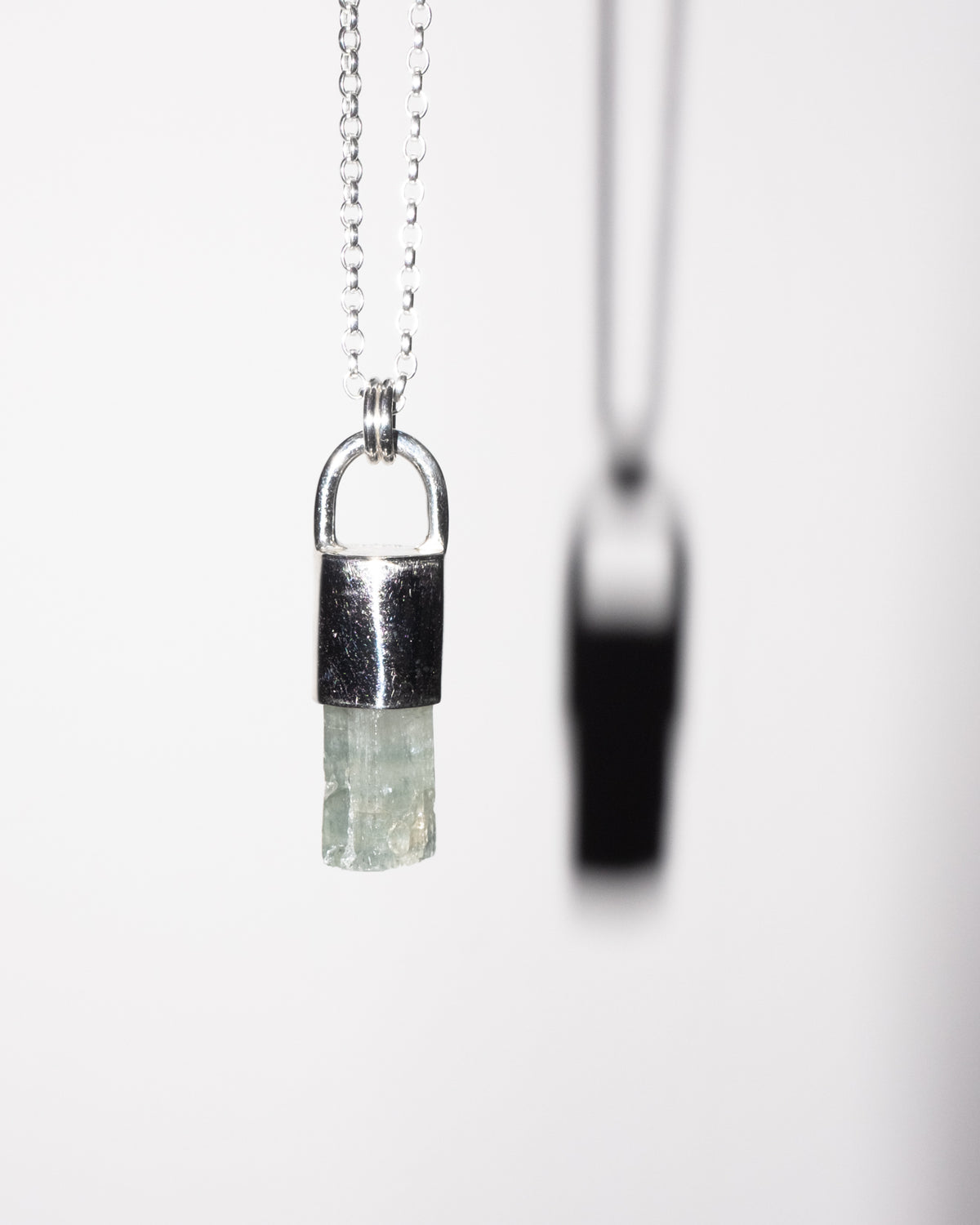 Raw aquamarine crystal set in sterling silver on a belcher chain, against a white background