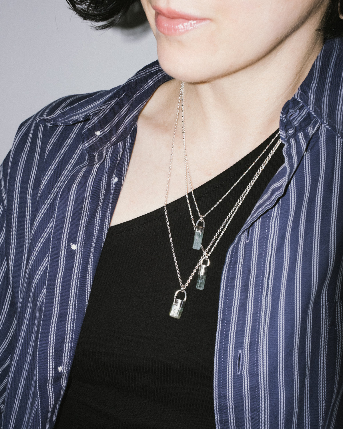 Model wearing the raw aquamarine sterling silver necklace layered with other chains