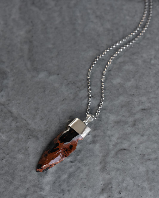 Mahogany obsidian arrowhead set in sterling silver on a sterling silver chain, on grey slate